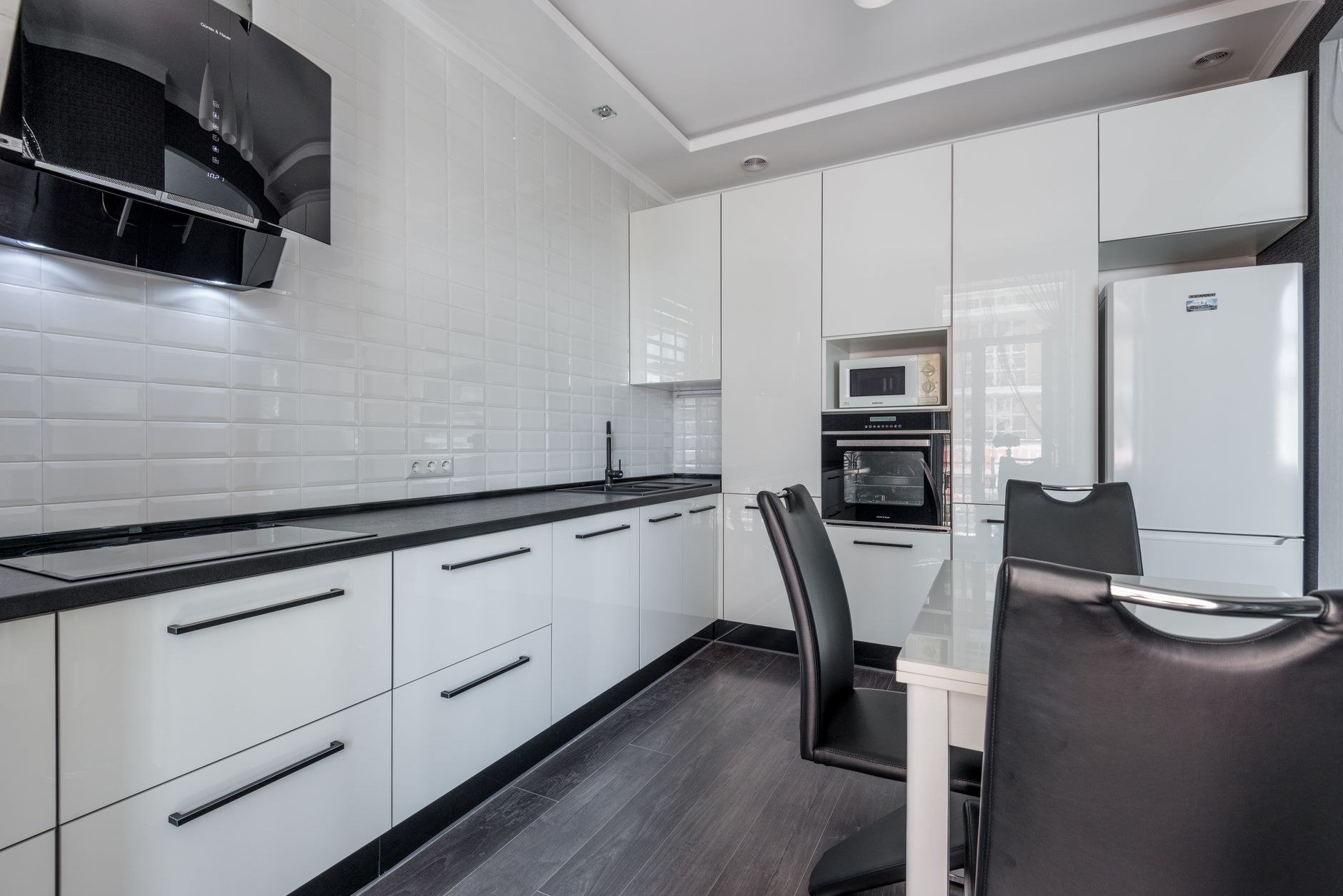 Sleek modern kitchen with white cabinets, black accents, and dining area in Riverside, CA